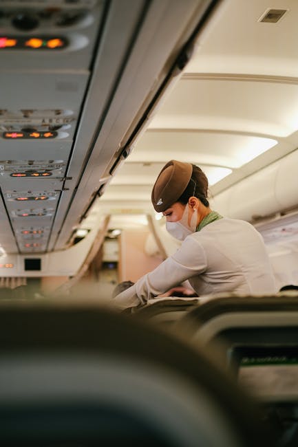 A flight attendant performs duties onboard a passenger airplane while wearing a protective mask.