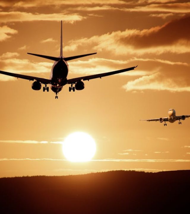 Silhouetted airplanes landing against a dramatic sunset sky, capturing the essence of flight.